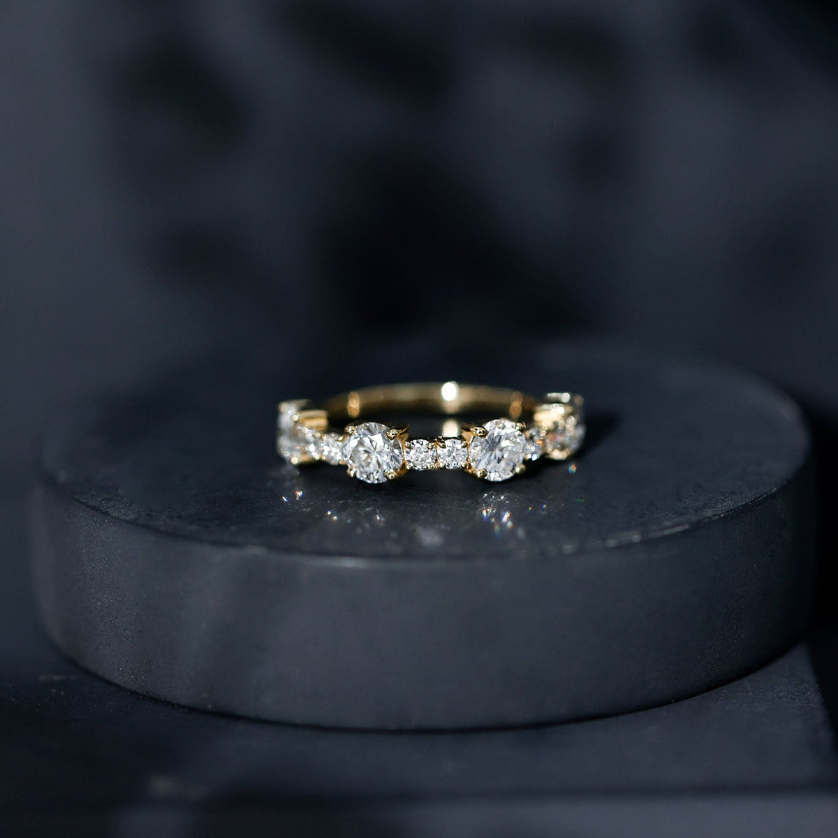 Round moissanite half eternity wedding band by Rosec Jewels featuring sparkling stones set in a sleek gold ring.