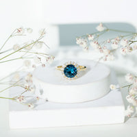 Two-carat round London Blue Topaz engagement ring with diamond halo, crafted by Rosec Jewels, featuring a classic design.