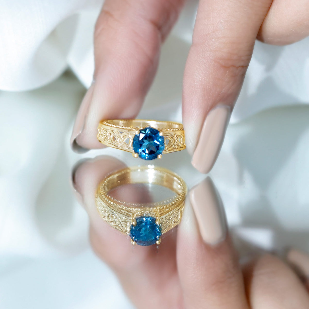 Round 1.35 carat London Blue Topaz vintage engagement ring with Celtic-style band, featuring intricate metalwork and gemstone centerpiece.