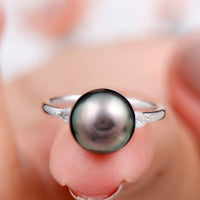 Round Tahitian pearl solitaire engagement ring with moissanite by Rosec Jewels, featuring a sleek band and a lustrous black pearl centerpiece.