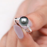 Round Tahitian pearl solitaire engagement ring with moissanite, featuring a sleek band and elegant pearl centerpiece.