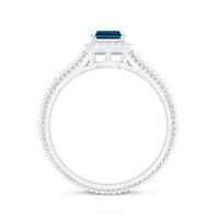 Emerald cut blue topaz engagement ring with diamond halo from Rosec Jewels, showcasing a sparkling blue gemstone and intricate band design.