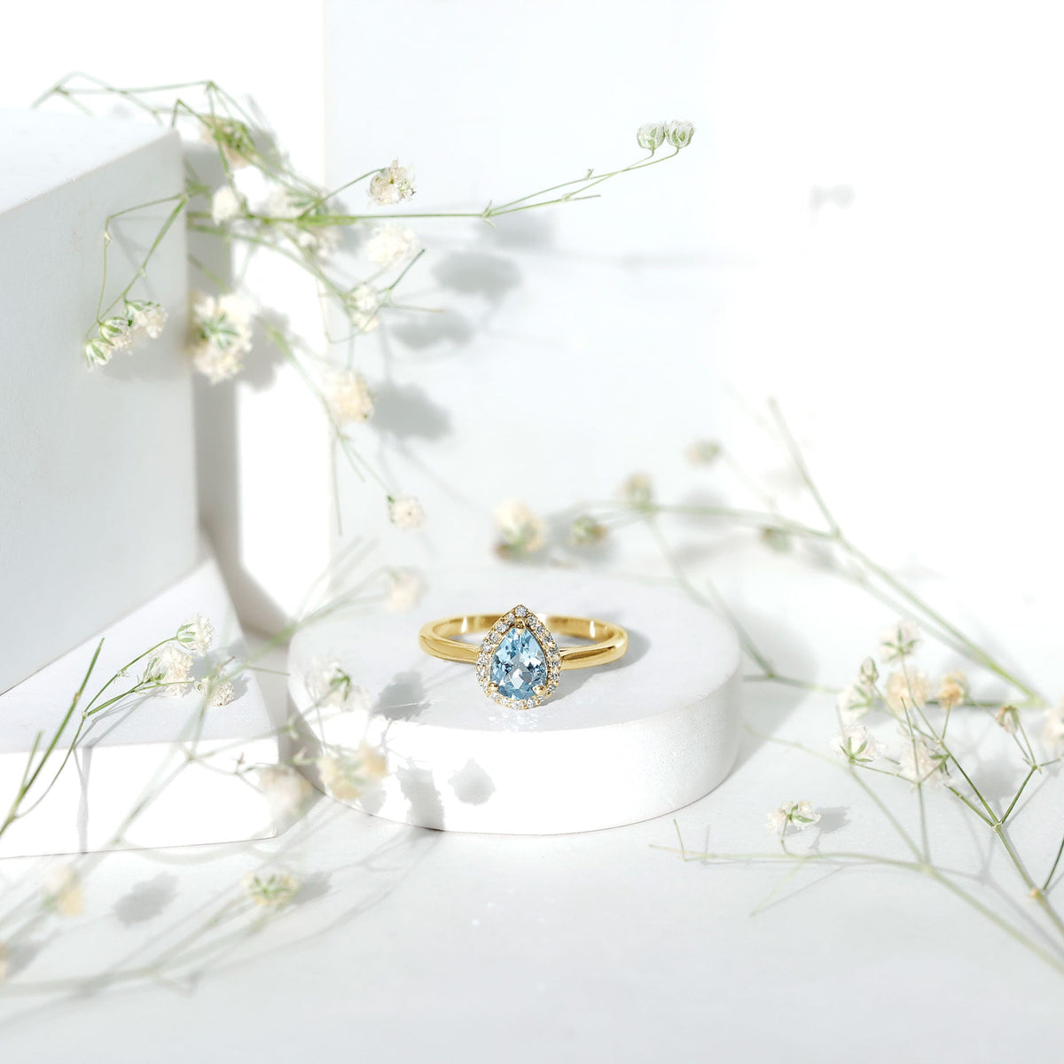 Pear-shaped 1-carat aquamarine engagement ring with diamond halo, shown from a side view, featuring intricate band details.