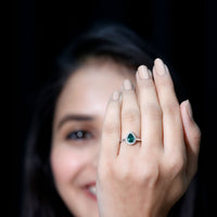 Emerald teardrop engagement ring with diamond halo from Rosec Jewels, showcasing a green emerald center and sparkling surrounding diamonds.