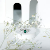 Real emerald teardrop engagement ring with diamond halo and rose gold band from Rosec Jewels, showcasing the intricate design and sparkling stones.