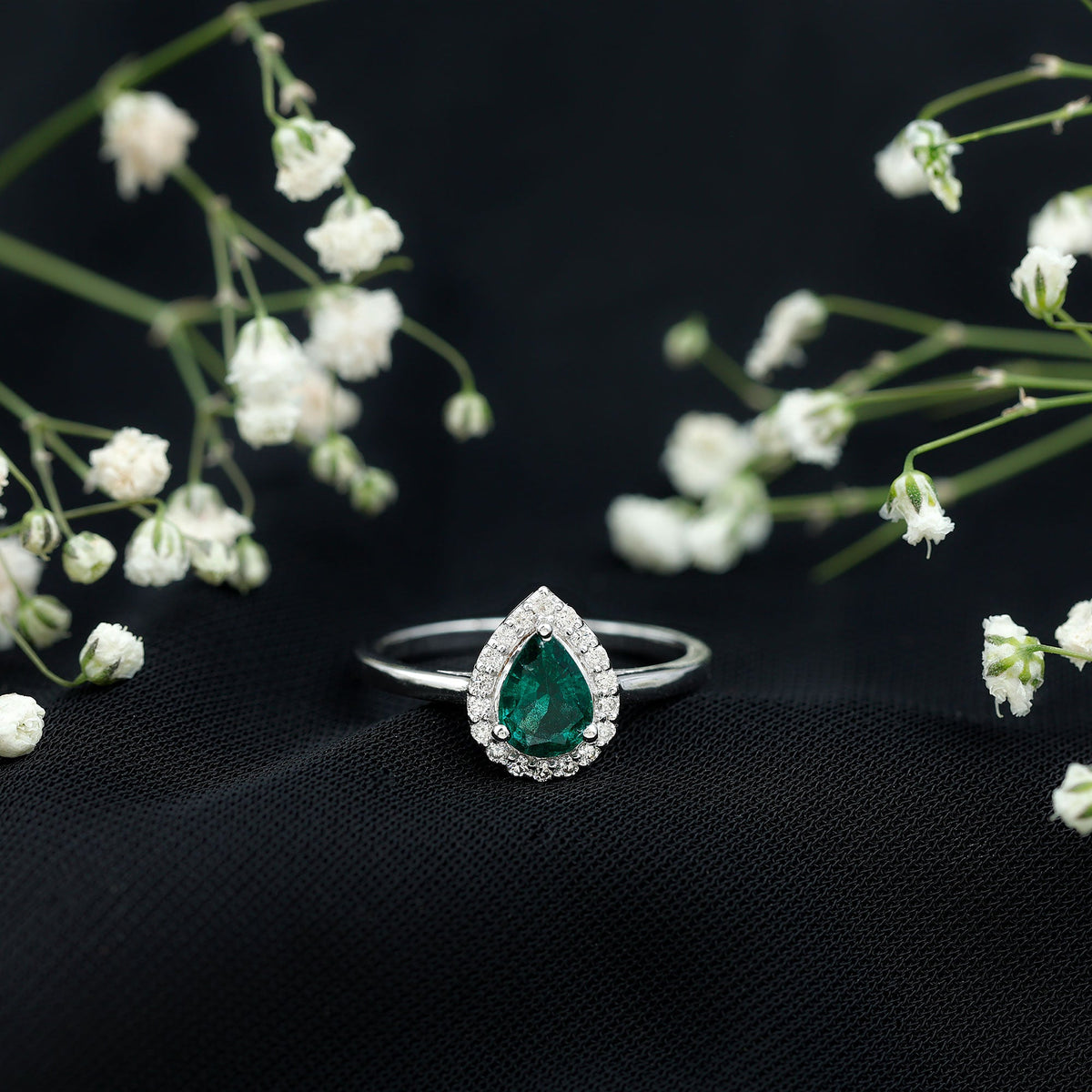 Elegant real emerald teardrop engagement ring with diamond halo from Rosec Jewels, showcasing a shimmering emerald center and sparkling diamonds.