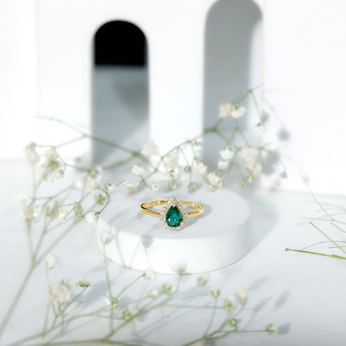 Real emerald teardrop engagement ring with diamond halo from Rosec Jewels, featuring a green emerald center and sparkling diamond accents.