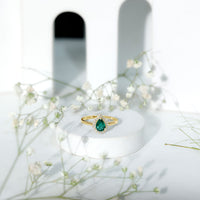 Real emerald teardrop engagement ring with diamond halo from Rosec Jewels, featuring a green emerald center and sparkling diamond accents.
