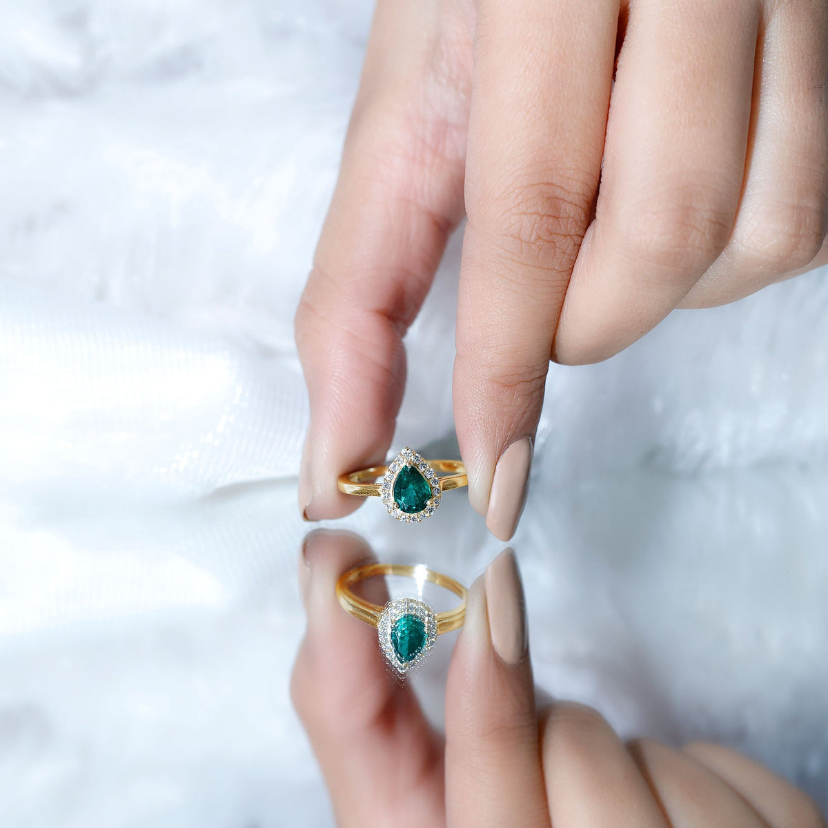 Real emerald teardrop engagement ring with diamond halo, showcasing a stunning green emerald center and sparkling diamond accents.