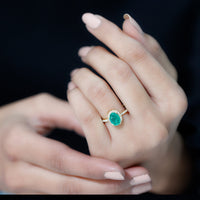 Genuine 6x8mm oval emerald engagement ring with diamond halo by Rosec Jewels, featuring a gold band and intricate detailing.
