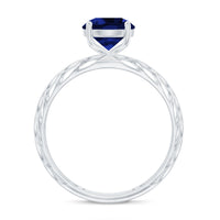 Lab-created blue sapphire solitaire ring with filigree shank, featuring intricate metalwork and a vibrant blue gemstone.