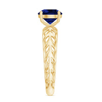 Lab-created blue sapphire solitaire ring with intricate filigree shank, featuring a sparkling blue gemstone and detailed metalwork.