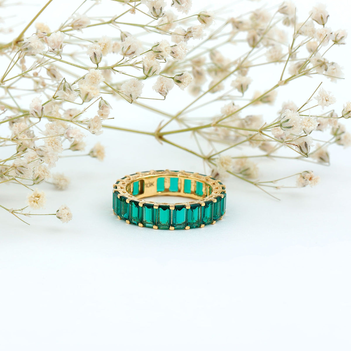 Emerald cut lab-grown emerald eternity wedding band by Rosec Jewels, featuring sparkling green gemstones in a continuous circle of rings.