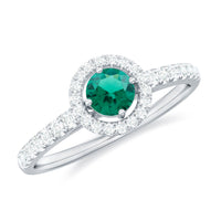 Certified lab-grown emerald diamond halo engagement ring with a silver band featuring a central emerald and surrounding sparkling diamonds.