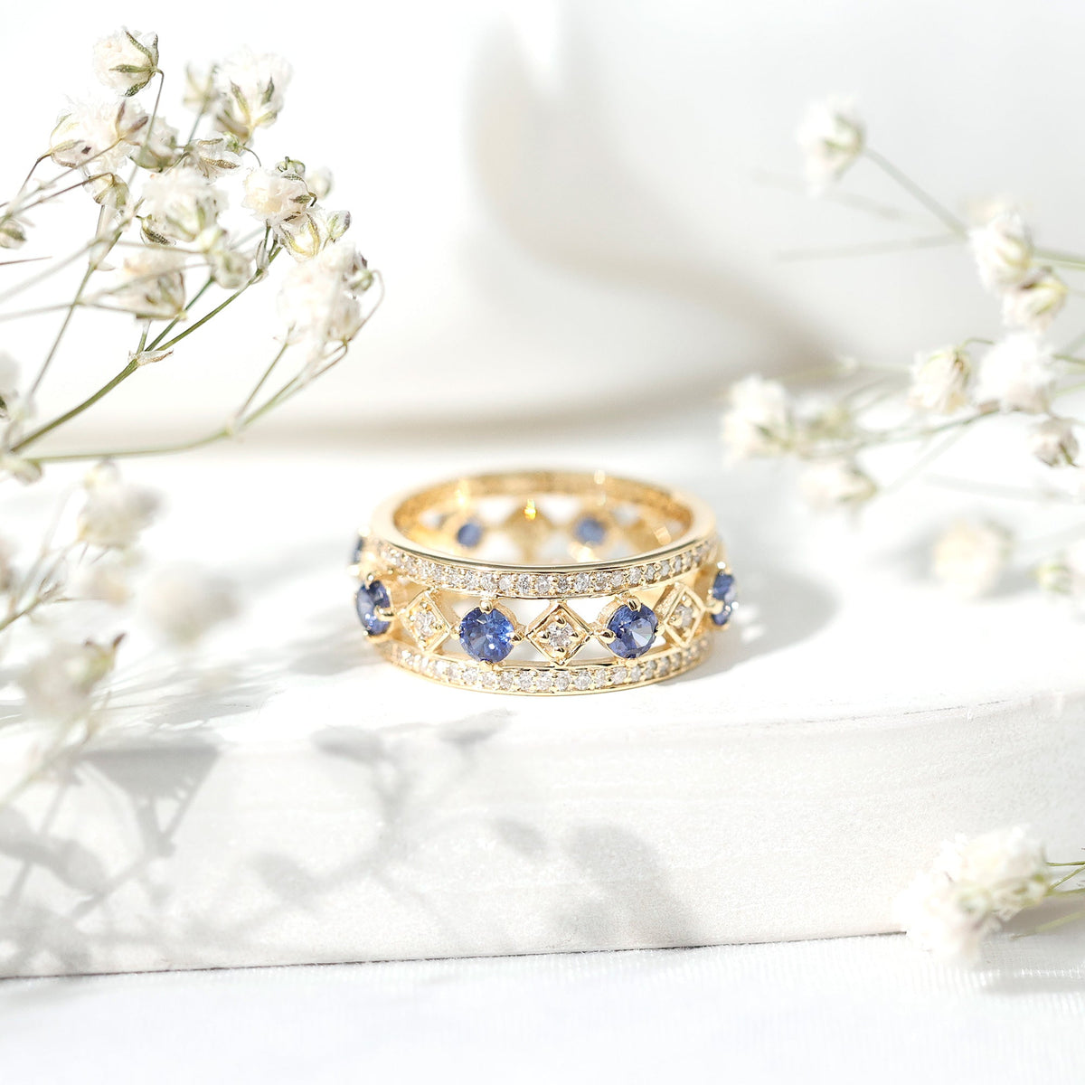 Lab-created blue sapphire and diamond eternity band ring by Rosec Jewels, showcasing a full circle of sparkling gemstones and elegant design.