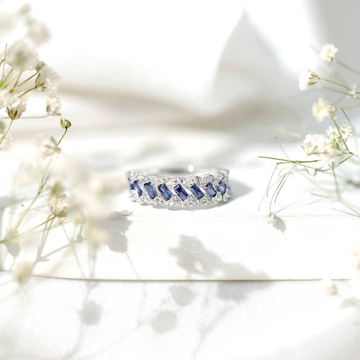 Rosec Jewels lab-grown blue sapphire half eternity ring with diamonds, showcasing a row of blue sapphires and sparkling diamonds.