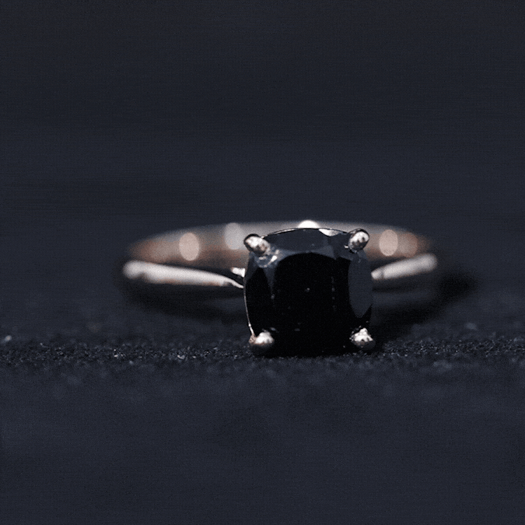 Black onyx solitaire engagement ring with cushion cut center stone, set in a sleek band, by Rosec Jewels.
