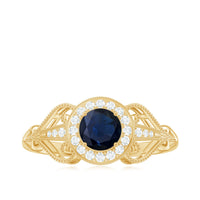 Vintage blue sapphire engagement ring with diamond halo, featuring intricate detailing and a sterling silver band from Rosec Jewels.