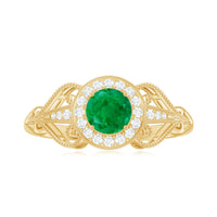 Vintage-inspired engagement ring with AAA quality emerald and diamonds featuring intricate detailing and a rose gold band.