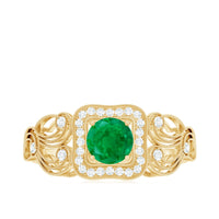 Vintage looking emerald engagement ring with diamond halo from Rosec Jewels, featuring intricate metalwork and sparkling gemstones.