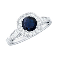 Round 0.9 carat blue sapphire antique engagement ring with diamond halo, featuring intricate metalwork and elegant design.