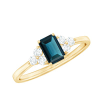 Emerald cut London Blue Topaz engagement ring with diamond trio setting, featuring a silver band and intricate detailing by Rosec Jewels.
