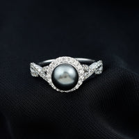 Real Tahitian pearl and diamond crossover engagement ring by Rosec Jewels, featuring a pearl and sparkling diamonds on a gold band.