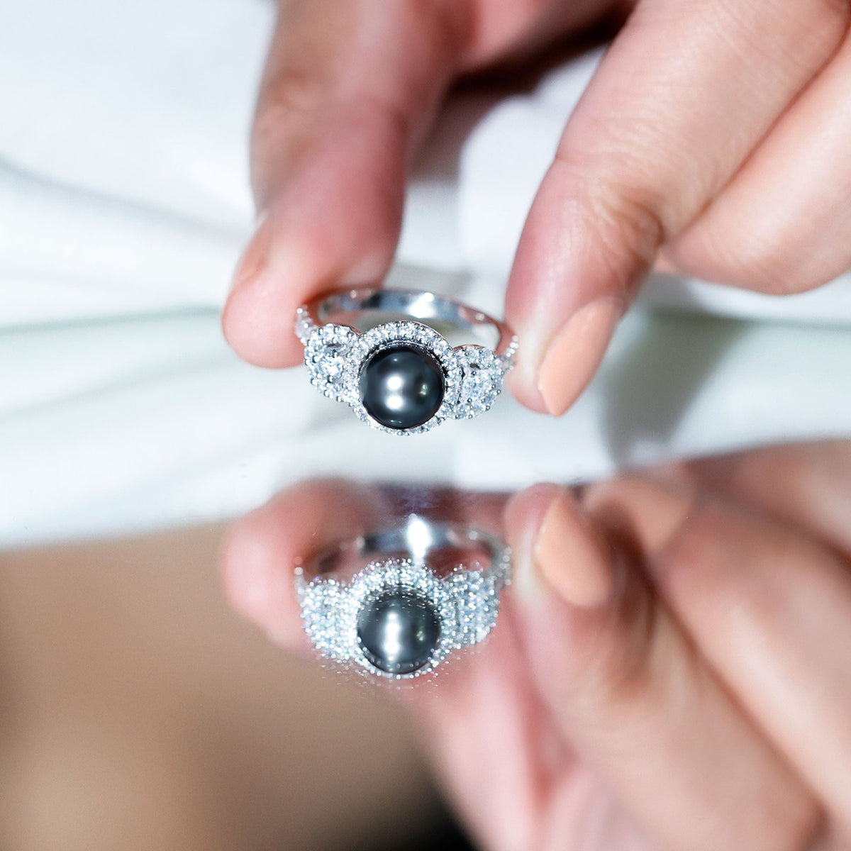 7.5 carat round black pearl engagement ring with moissanite accents, featuring a Rosec Jewels ring in a close-up shot.
