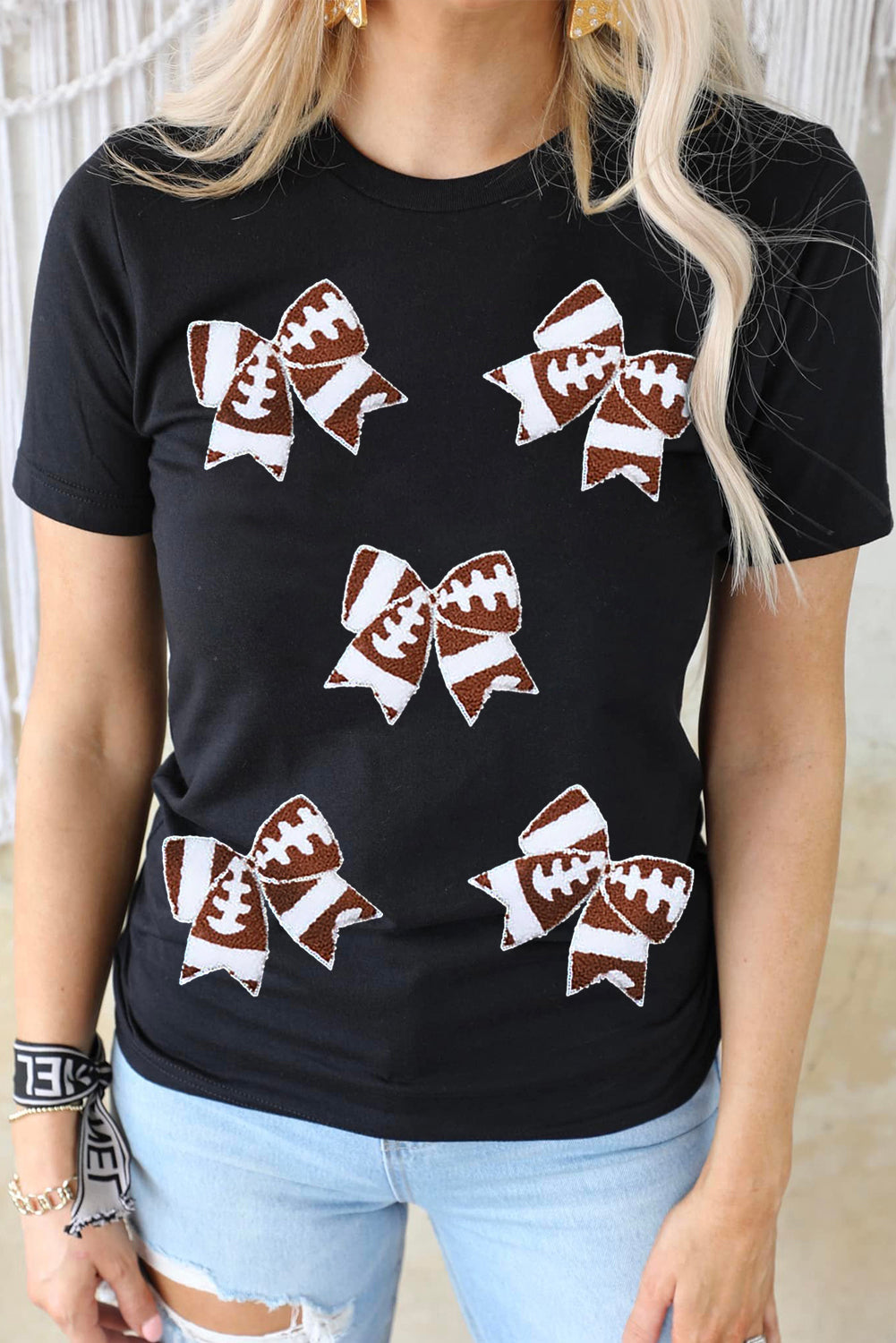 Black football-themed T-shirt with bowknot pattern from Adelyne's Boutique, ideal for game day and casual wear.