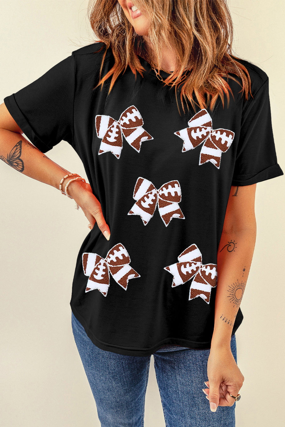 Black football-themed T-shirt with bowknot pattern, perfect for game day, from Adelyne's Boutique & Gifts.