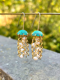 Green copper jellyfish earrings with white pearls and sterling silver earwires by Alison Morse, hanging delicately.