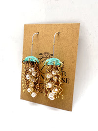 Green copper jellyfish earrings with white pearls and sterling silver earwires by Alison Morse, shown on packaging.