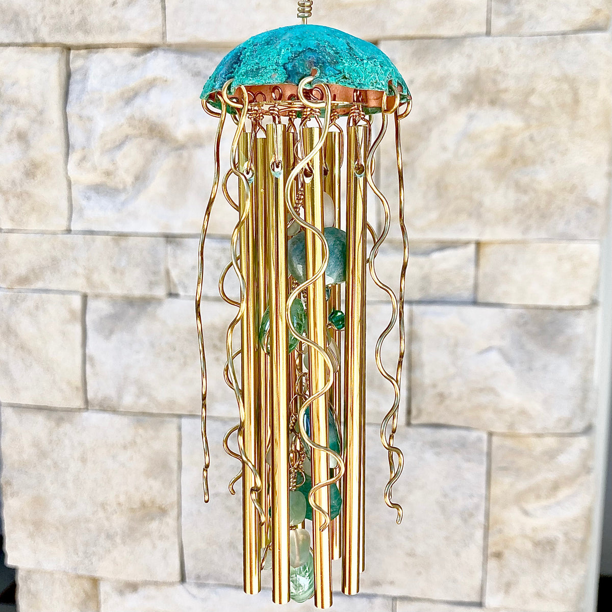 Colorful Alison Morse jellyfish wind chime hanging outdoors with flowing ribbons and delicate glass jellyfish design.