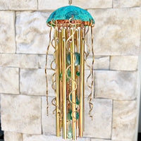 Colorful Alison Morse jellyfish wind chime hanging outdoors with flowing ribbons and delicate glass jellyfish design.