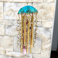 Colorful jellyfish-shaped wind chime by Alison Morse hanging outdoors with ocean-themed design and glass elements.