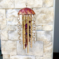 Colorful jellyfish-shaped wind chime by Alison Morse hanging outdoors, featuring translucent glass and hanging metal accents.