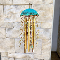 Colorful Alison Morse jellyfish wind chime hanging outdoors with glass bell-shaped pieces and ocean-inspired design.