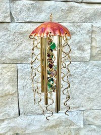 Colorful glass jellyfish wind chime by Alison Morse hanging outdoors, with vibrant, translucent jellyfish shapes and gentle movement.