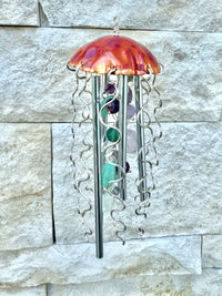 Colorful jellyfish-shaped wind chime by Alison Morse hanging outdoors with ocean-themed design and glass bell details.