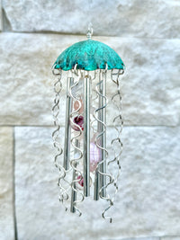 Colorful jellyfish-shaped wind chime by Alison Morse hanging outdoors with seashell accents and gentle movement.