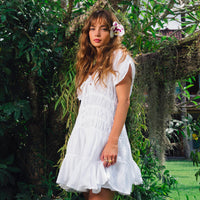 White The Srikandi Mini Ruffle Dress by BrunnaCo, featuring ruffle details and a stylish mini length, shown on a model.