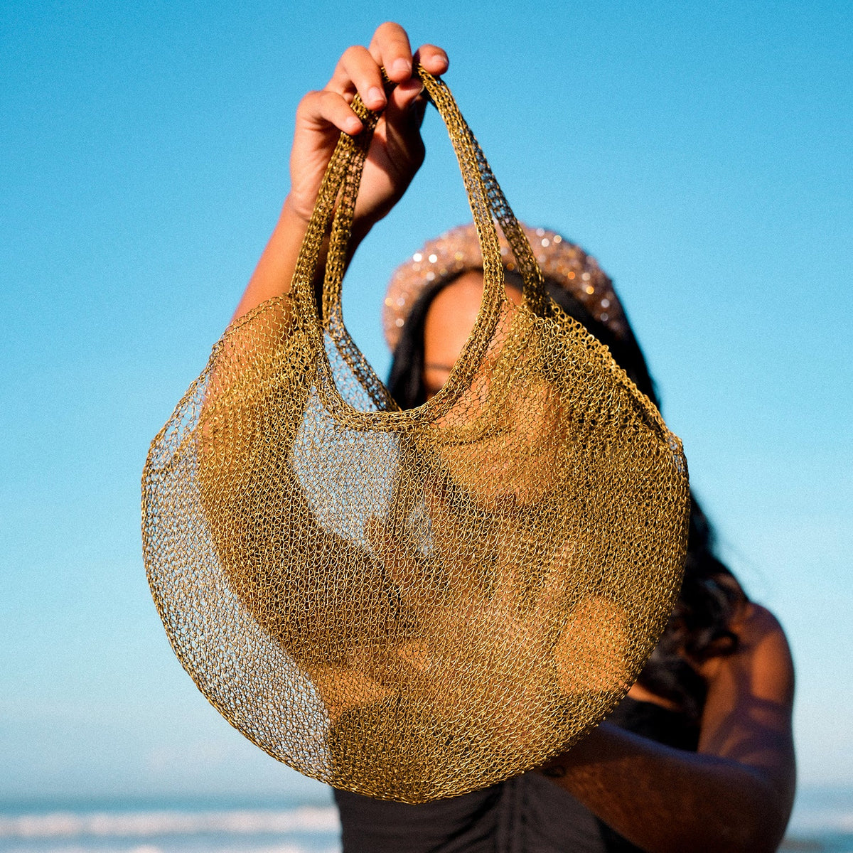 Dark gold mesh wire tote bag by BrunnaCo with sturdy handles, transparent design, and spacious interior for versatile use.