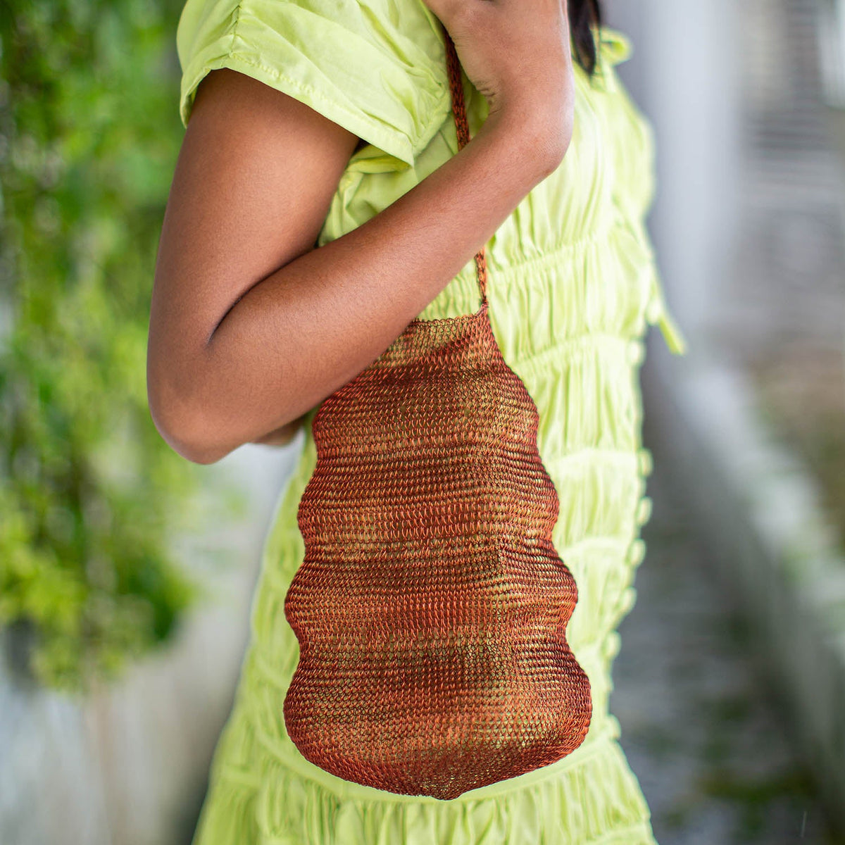 BrunnaCo The Shell handwoven wire handbag in copper, showcasing a unique round design with intricate wire detailing.