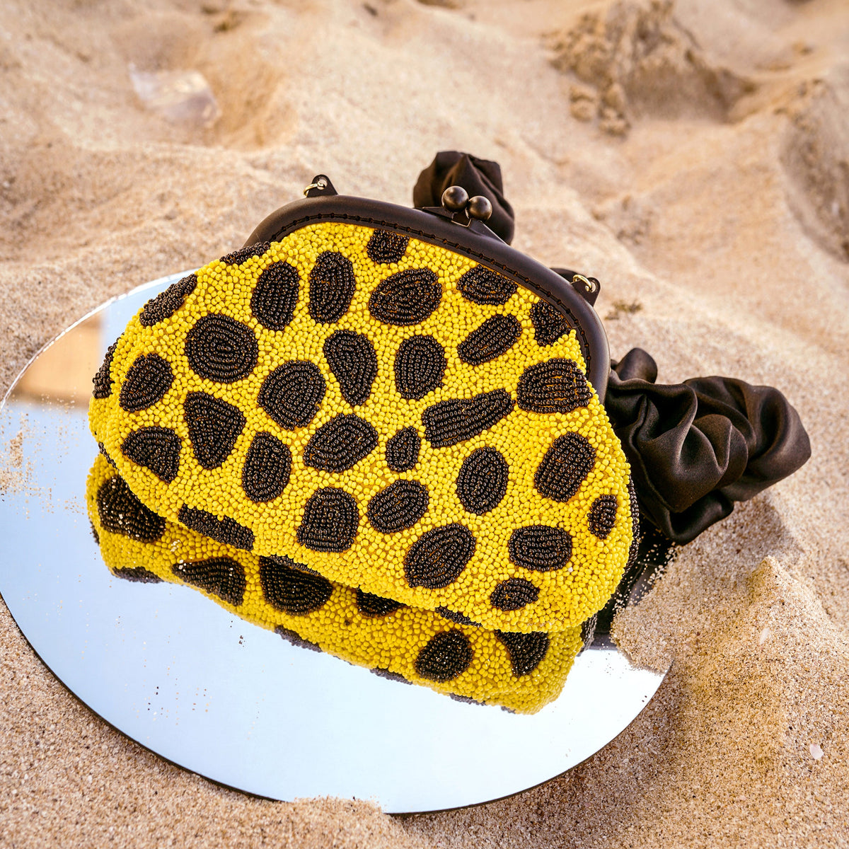 BrunnaCo Arnoldi Venom clutch bag in black and yellow with polka dots and glass bead accents, stylish handbag for evening wear.