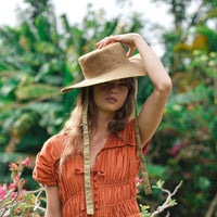 BrunnaCo The Loli Jute Straw Sun Hat in neutral beige with wide brim, lightweight straw material, perfect for sunny outdoor wear.