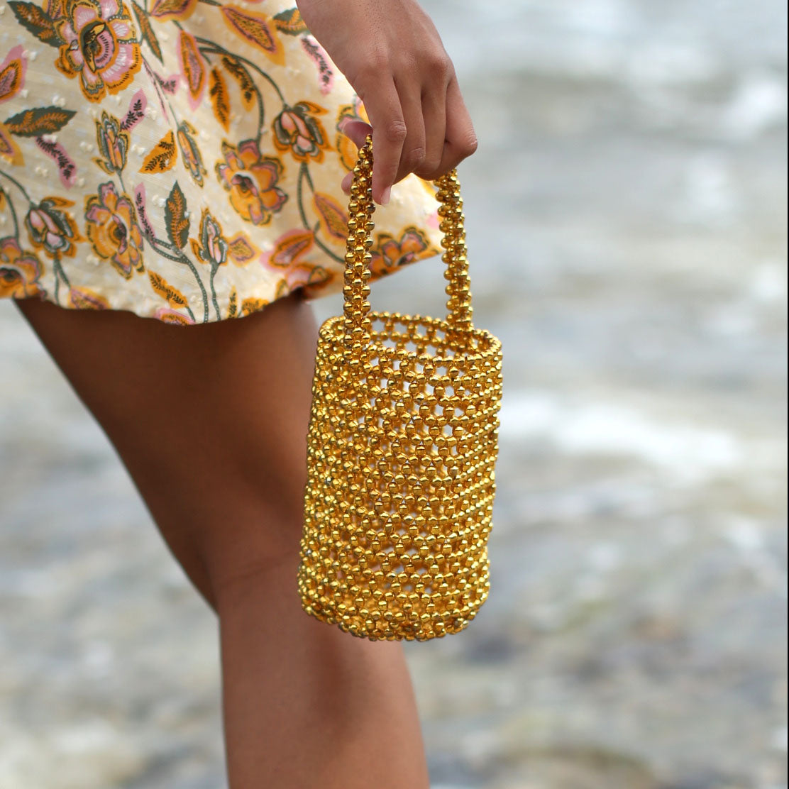 BrunnaCo GOLDA metallic beads bucket tote bag in gold with rounded handles and shiny textured surface.