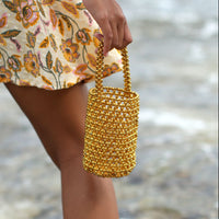 BrunnaCo GOLDA metallic beads bucket tote bag in gold with rounded handles and shiny textured surface.