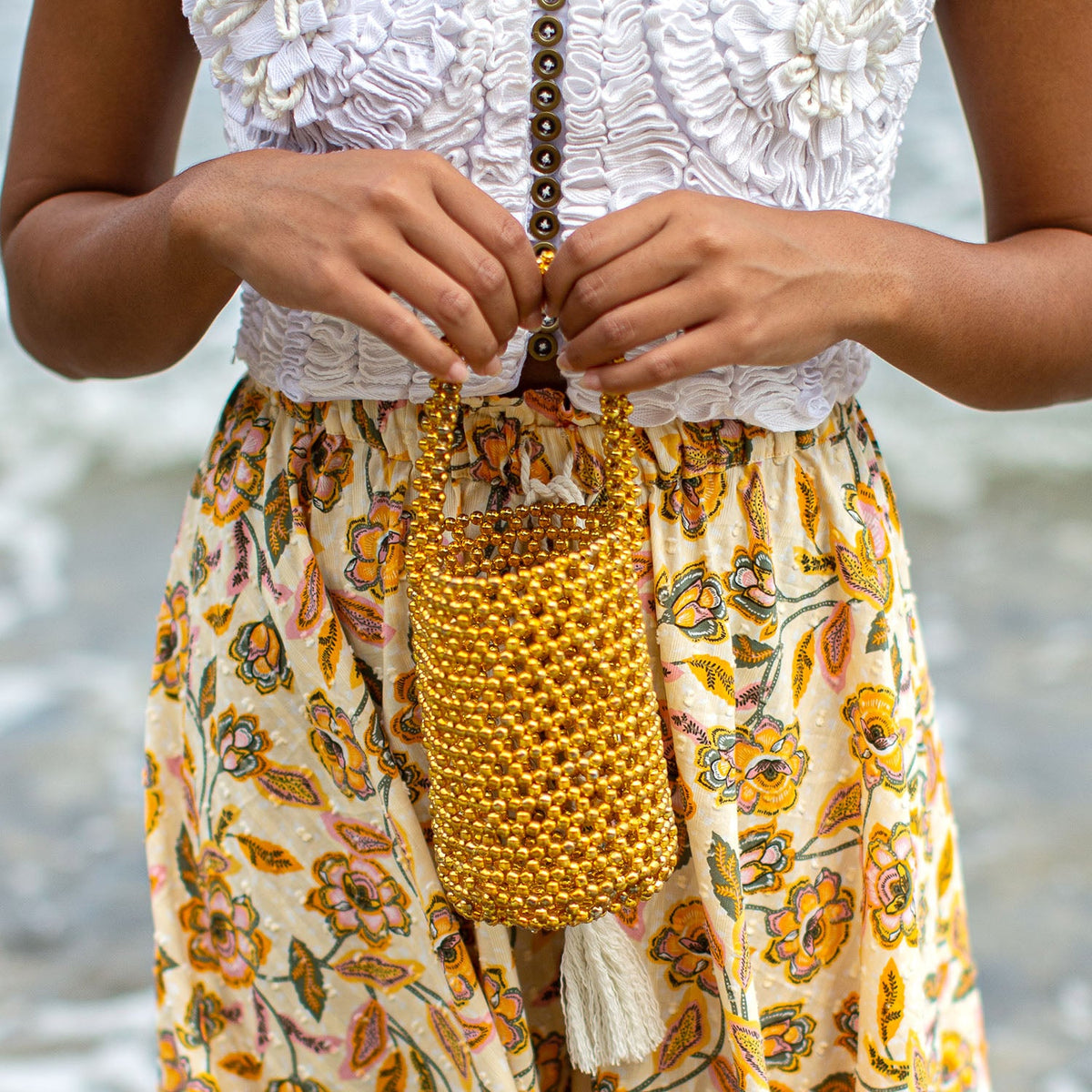 Gold metallic beads bucket tote bag by BrunnaCo featuring a shiny gold finish and stylish hand handle.