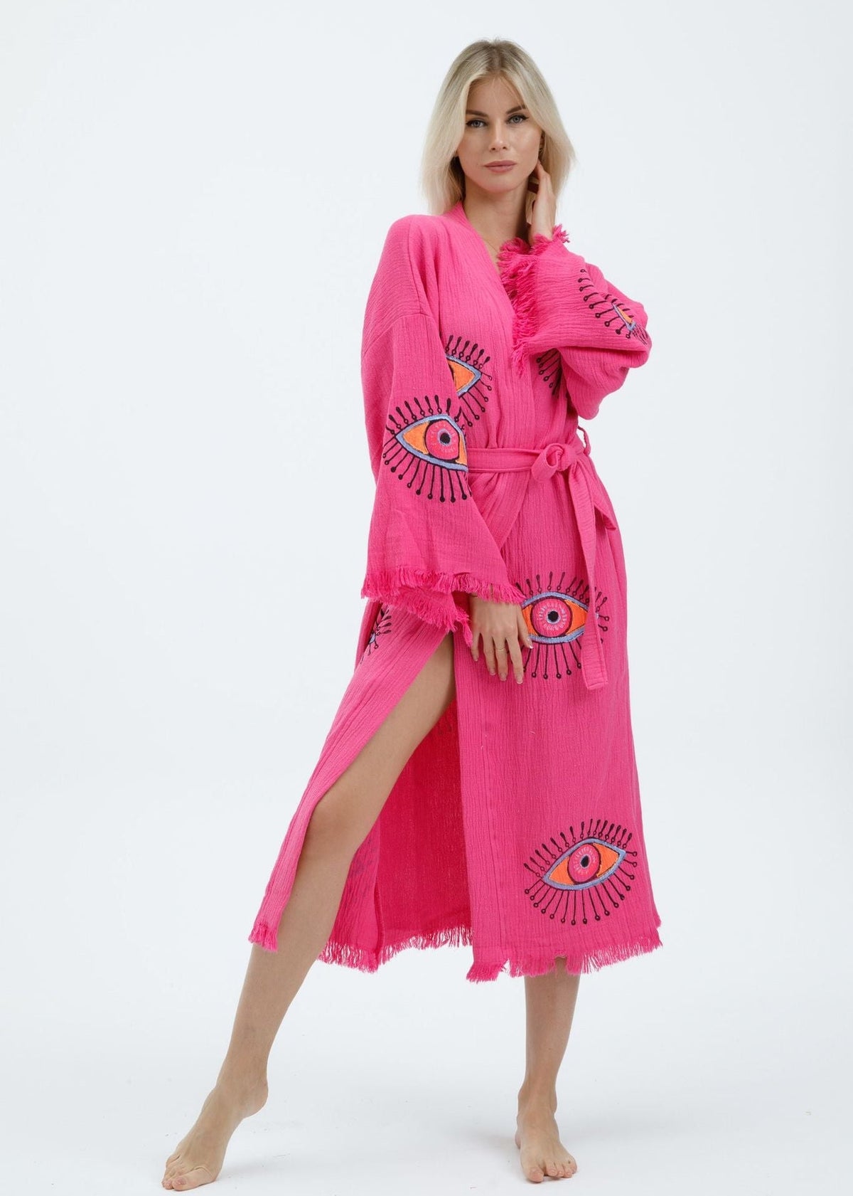 Black evil eye hand-printed kimono by Buldano, featuring natural fabric and intricate design, displayed hanging on a wooden stand.