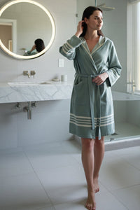 Woman wearing a green lightweight Turkish cotton bathrobe with hood, made from organic Turkish towel fabric, by Buldano.